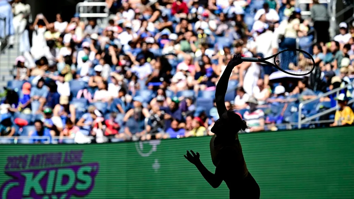 A player serves in silhouette in front of spectators during US Open Fan Week on August 23, 2026