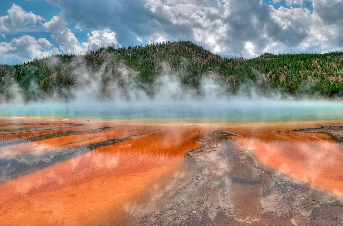 Steam rises above the orange and turquoise Grand Prismatic Spring in Yellowstone National Park