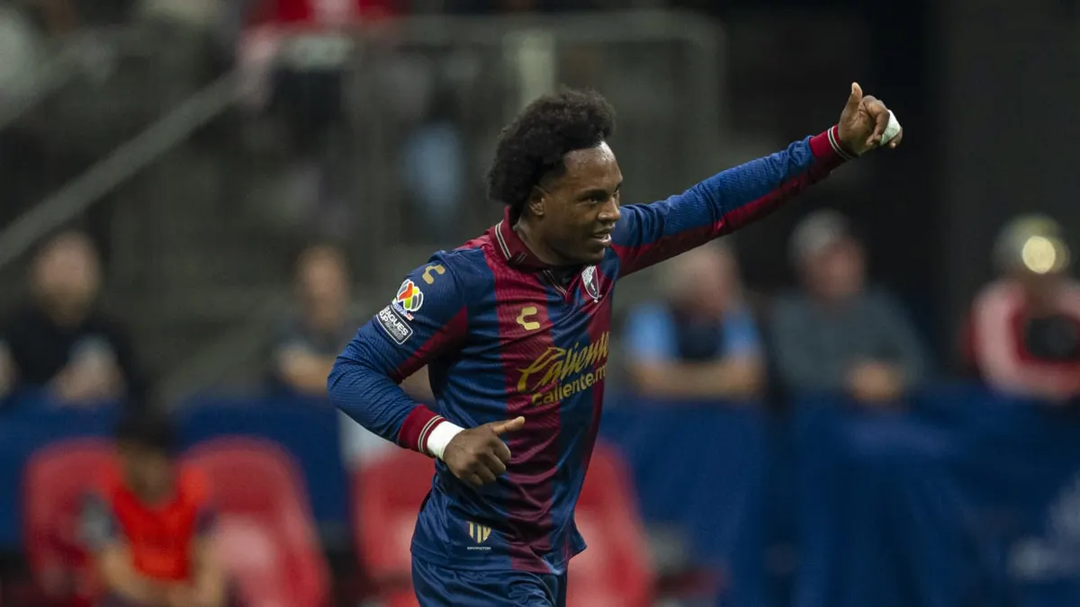 A Leagues Cup player in a blue and red striped jersey celebrates on the field