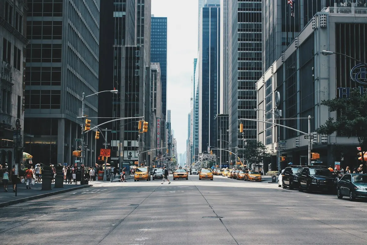 Pedestrians and taxis on an avenue between office buildings in New York City