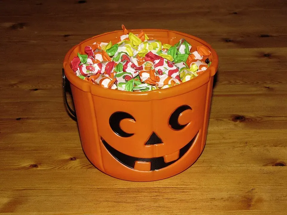 A pumpkin-shaped bucket filled with individually wrapped Halloween candy