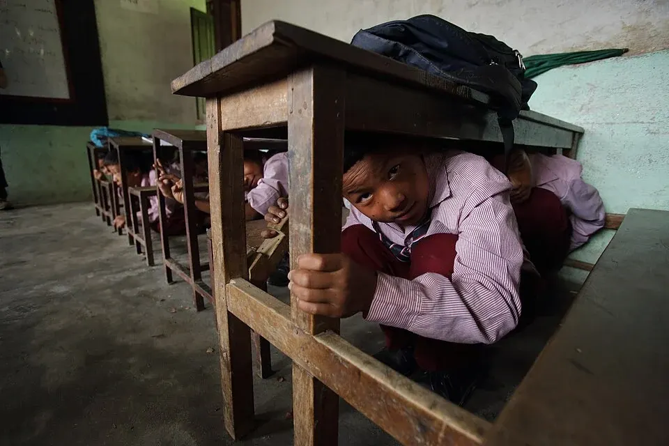 Students shelter beneath classroom desks during an earthquake drill