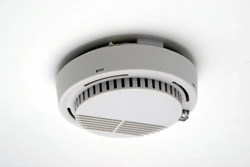 A round smoke alarm mounted on a ceiling