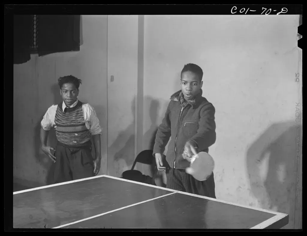 Two young people play table tennis in a recreation room in a 1942 photograph