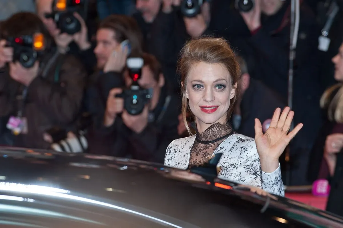 Heike Makatsch waves from a car at a Berlin film festival appearance