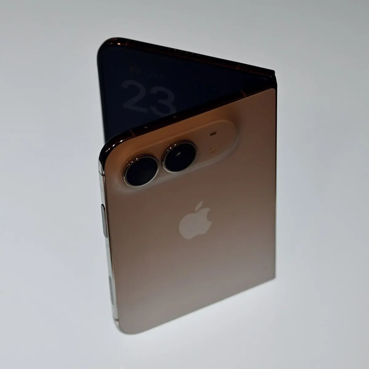 Gold-colored iPhone Duo standing partly folded against a pale background