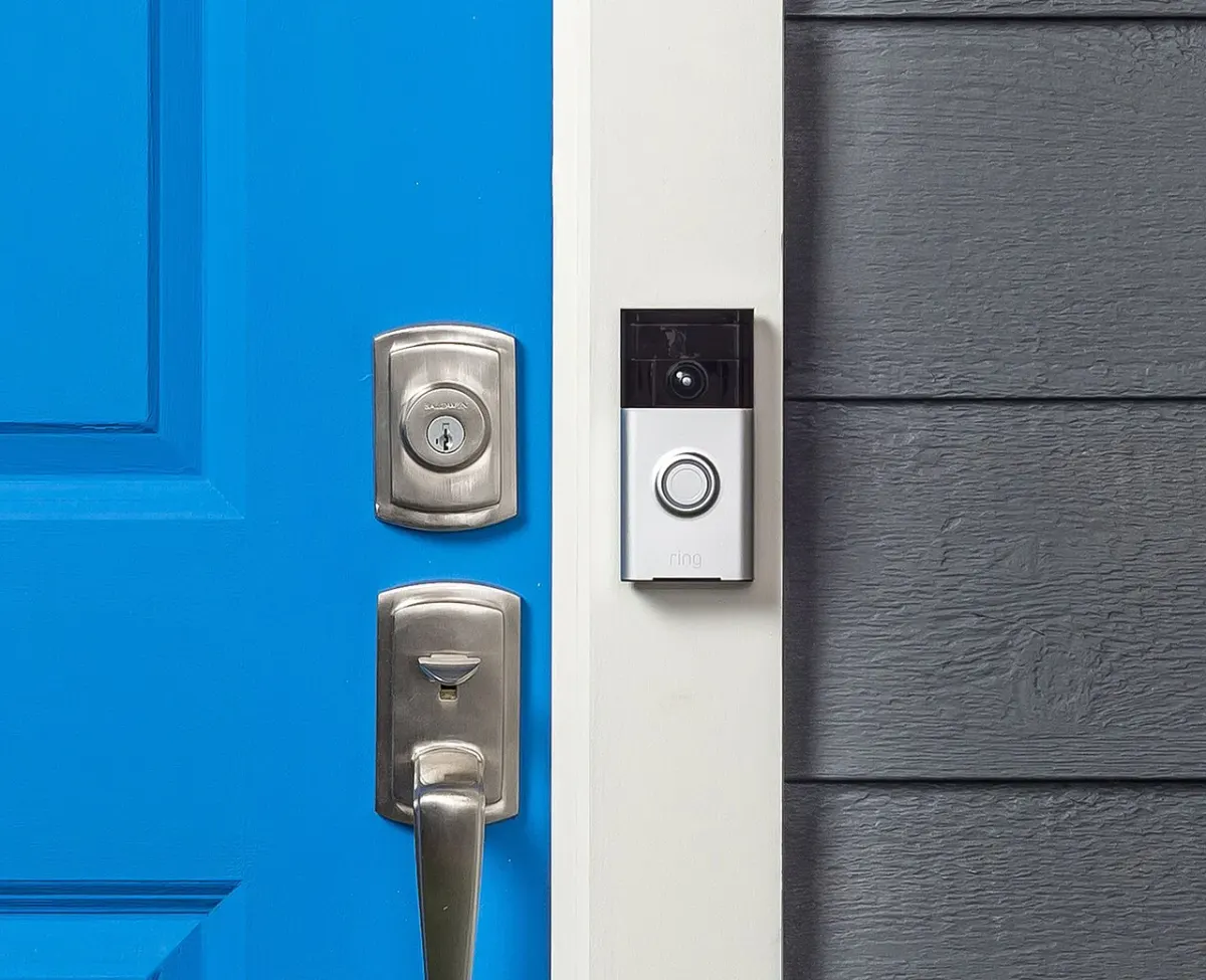 Ring video doorbell mounted beside the lock on a blue front door