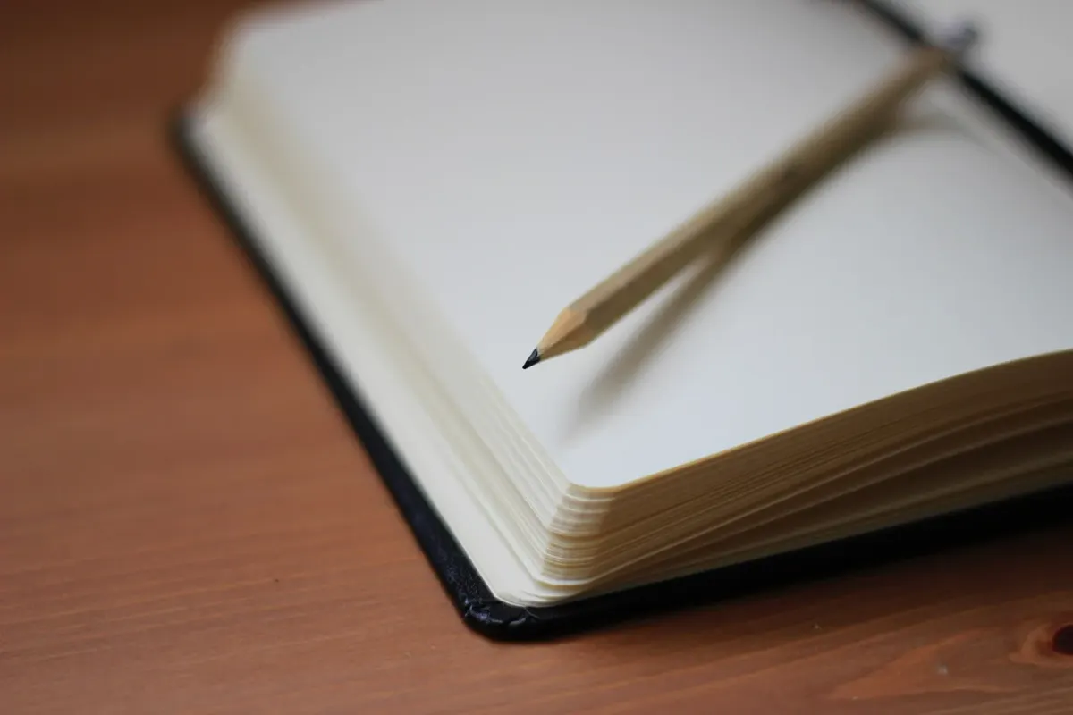 An open notebook and pencil on a wooden surface