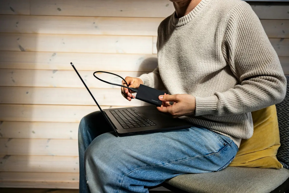 A person connecting a portable external drive to a laptop
