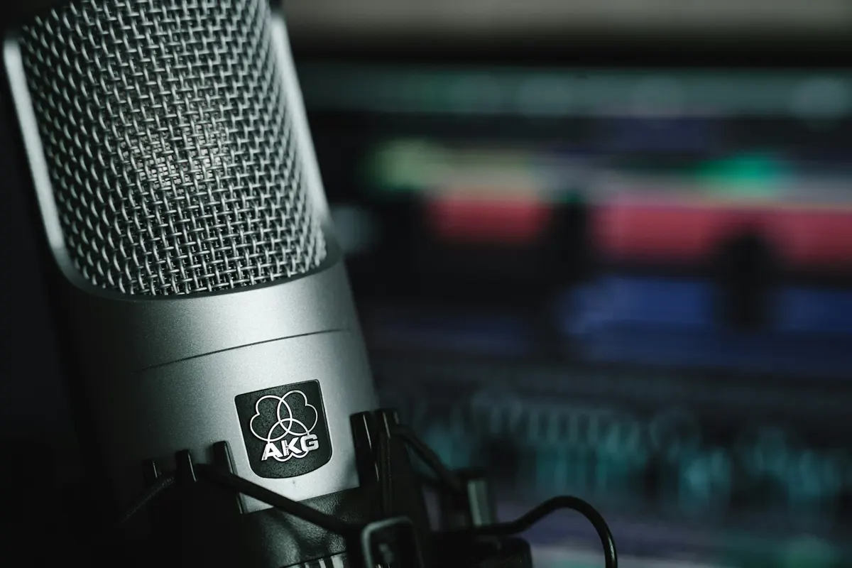 A silver studio microphone beside recording equipment