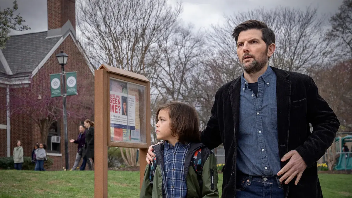 Adam Scott and a child beside a missing-person notice board in a still from The Whisper Man