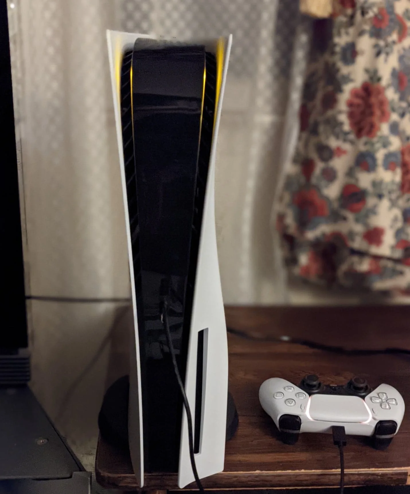 A white PlayStation 5 console beside a charging DualSense controller