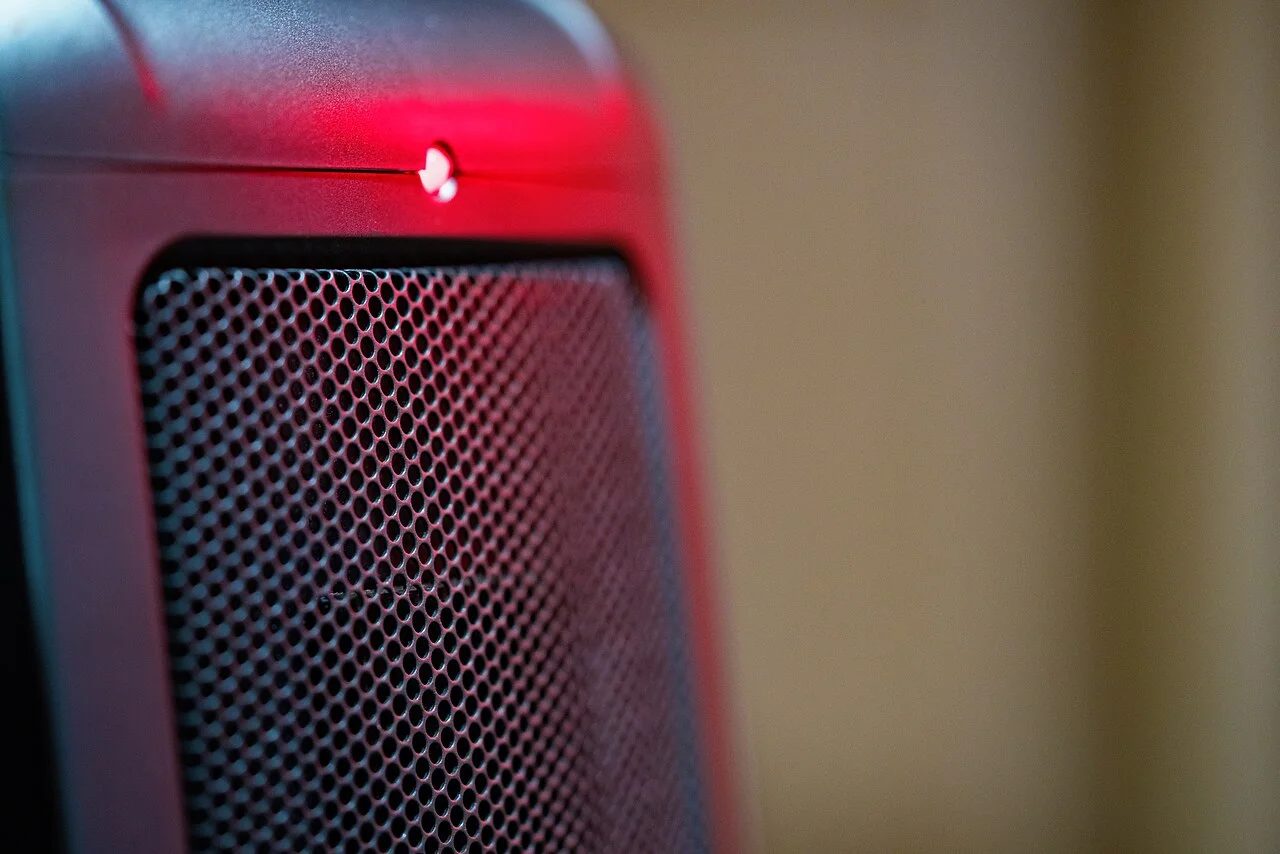 Close-up of a ceramic electric space heater grille and red indicator light.
