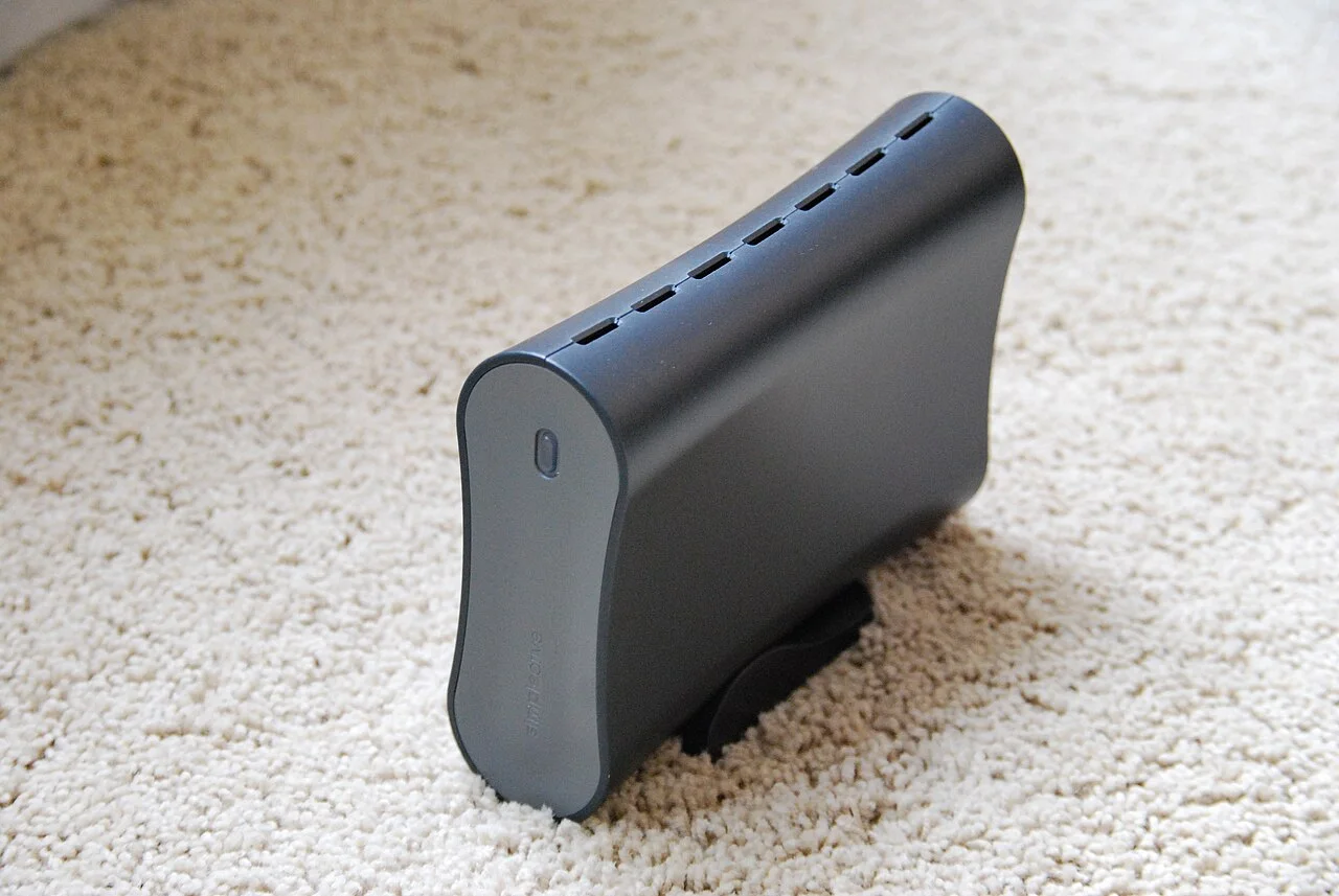 Gray external hard drive standing upright on beige carpet.