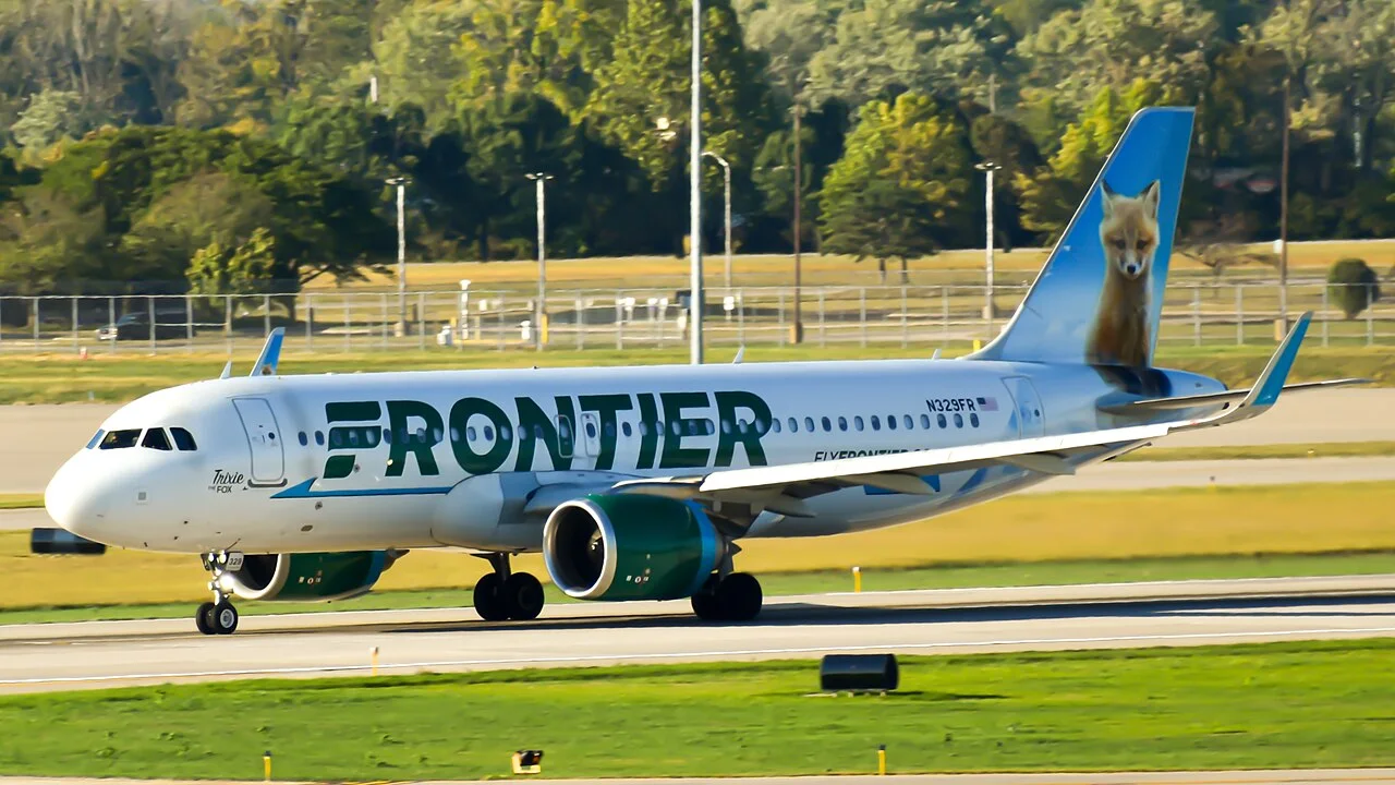 A white Frontier Airlines Airbus A320neo with a fox painted on its tail on an airport runway