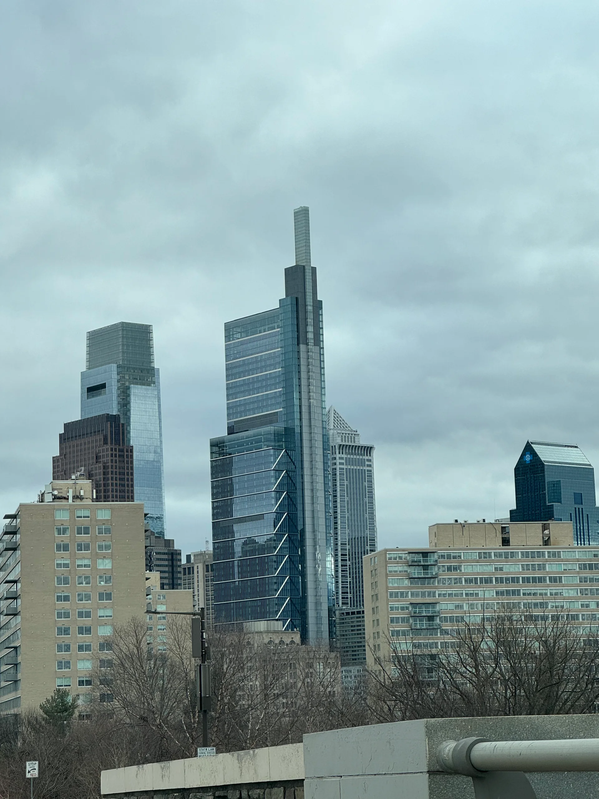 Comcast Technology Center rises above neighboring buildings in Philadelphia, viewed from Fairmount Park.