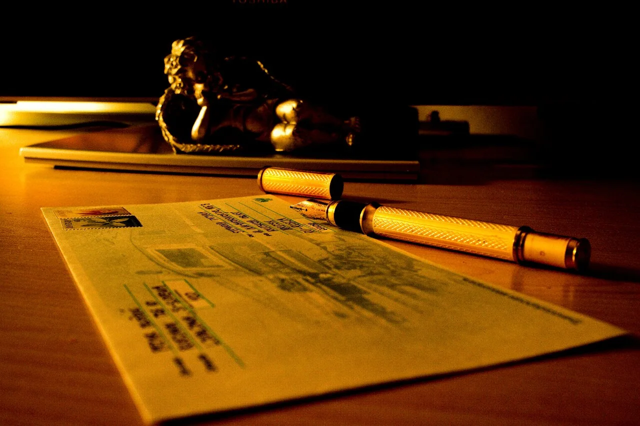 A fountain pen rests on an addressed envelope on a desk.