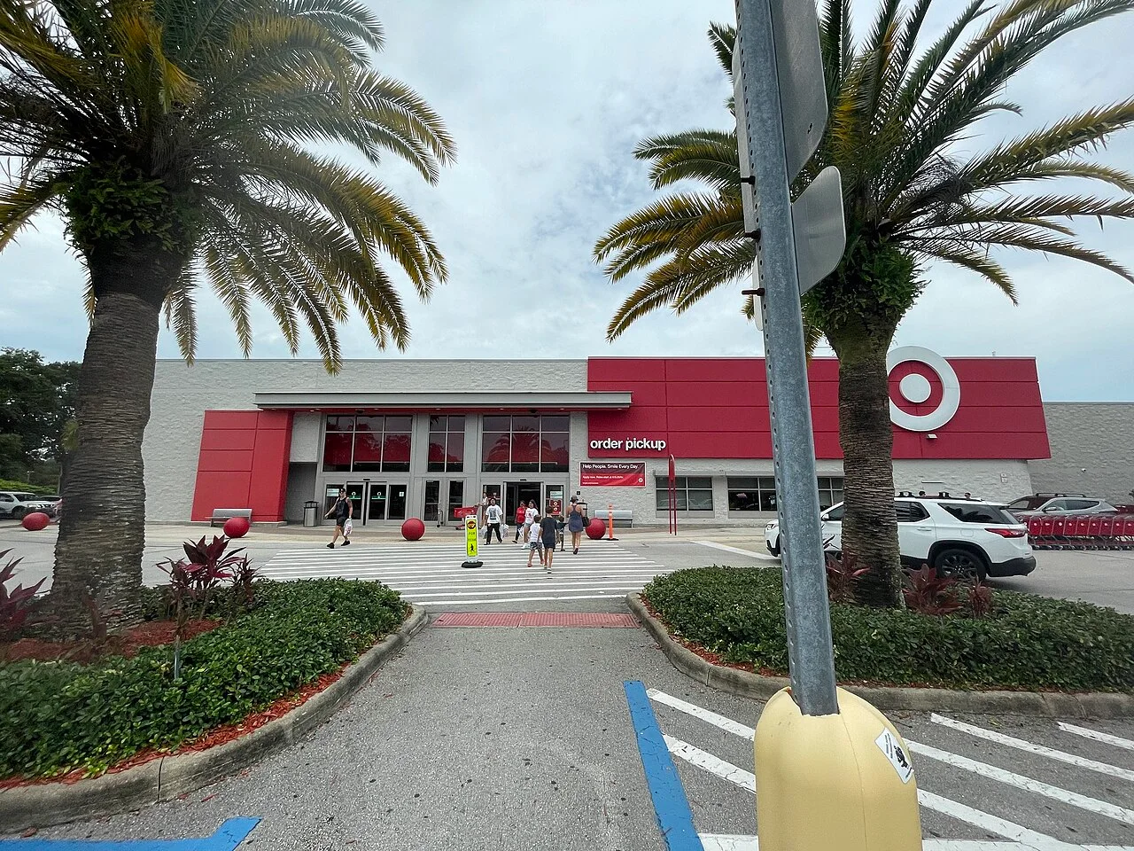 The red-and-gray front of a Target store with an order pickup sign, palm trees and a crosswalk in the parking lot