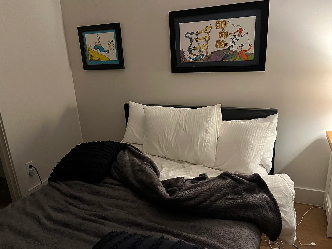 An unmade bed with white pillows and a dark blanket in a San Diego rental room.