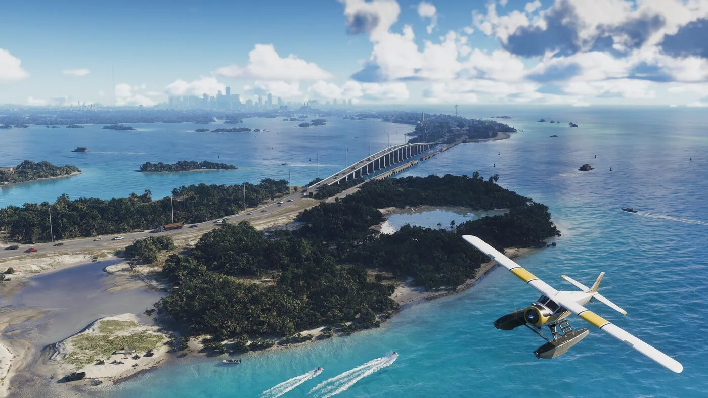 A yellow and white seaplane flying over green islands and a long bridge across turquoise water
