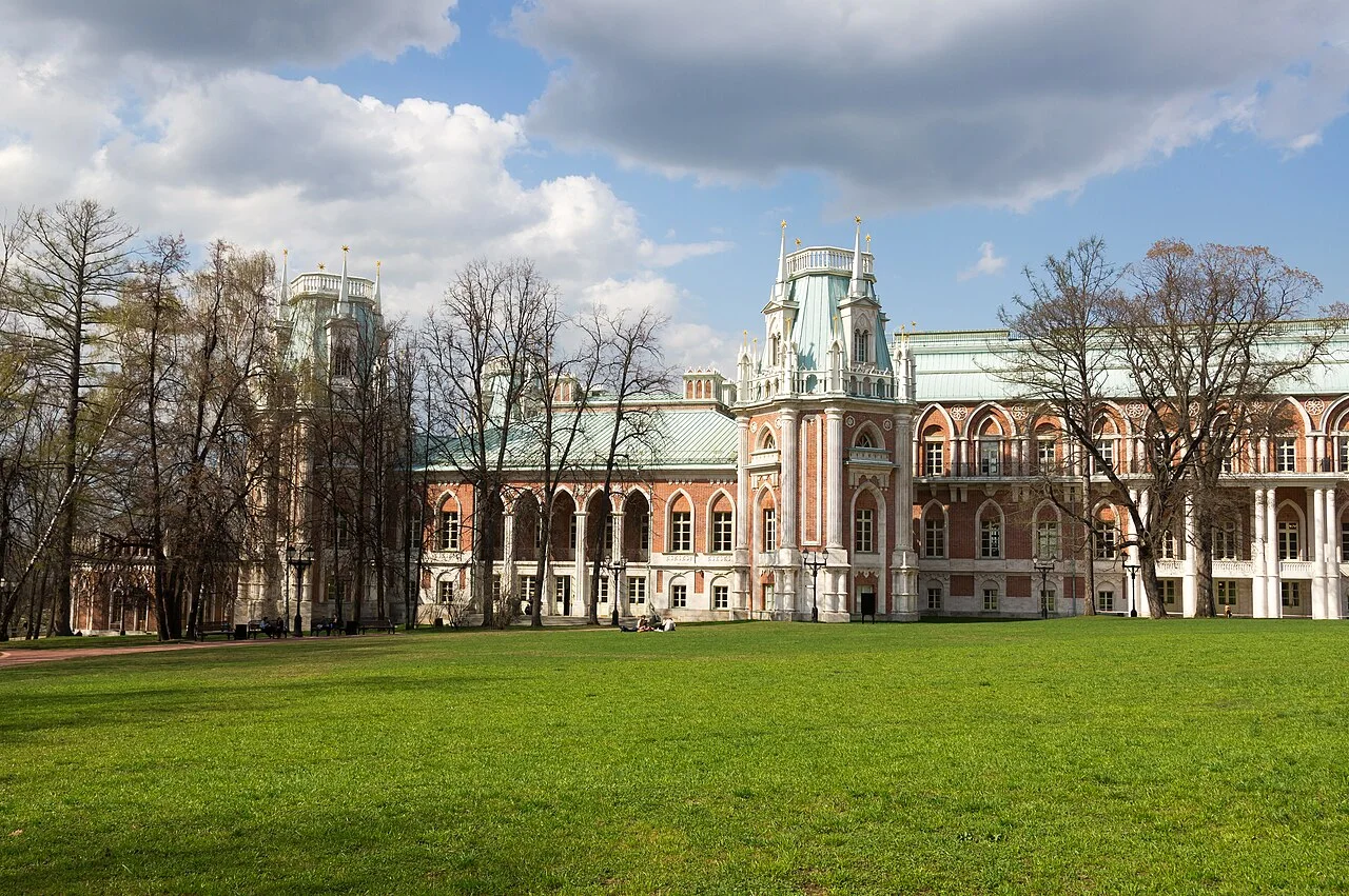 Red brick Tsaritsyno Palace with green roofs, trees and a lawn