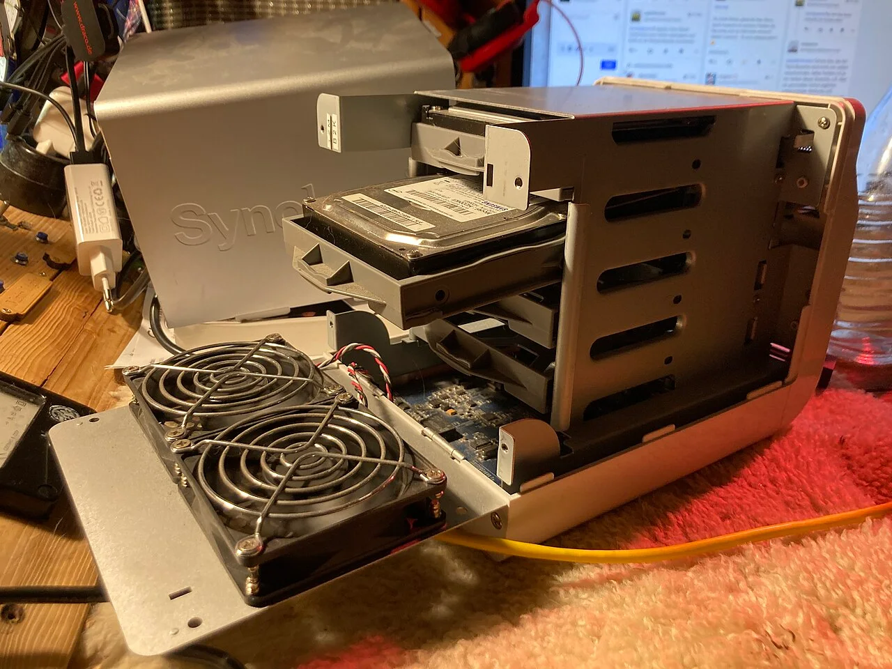 Open Synology DS413j enclosure showing drive bays, a hard drive and cooling fans.