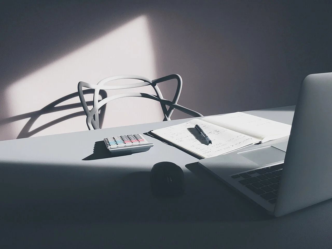 Calculator and open notebook beside a laptop on a desk