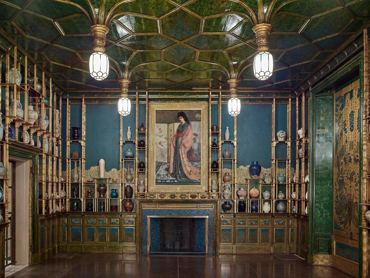 Blue-and-gold Peacock Room with ceramics on shelves and a painting above the fireplace