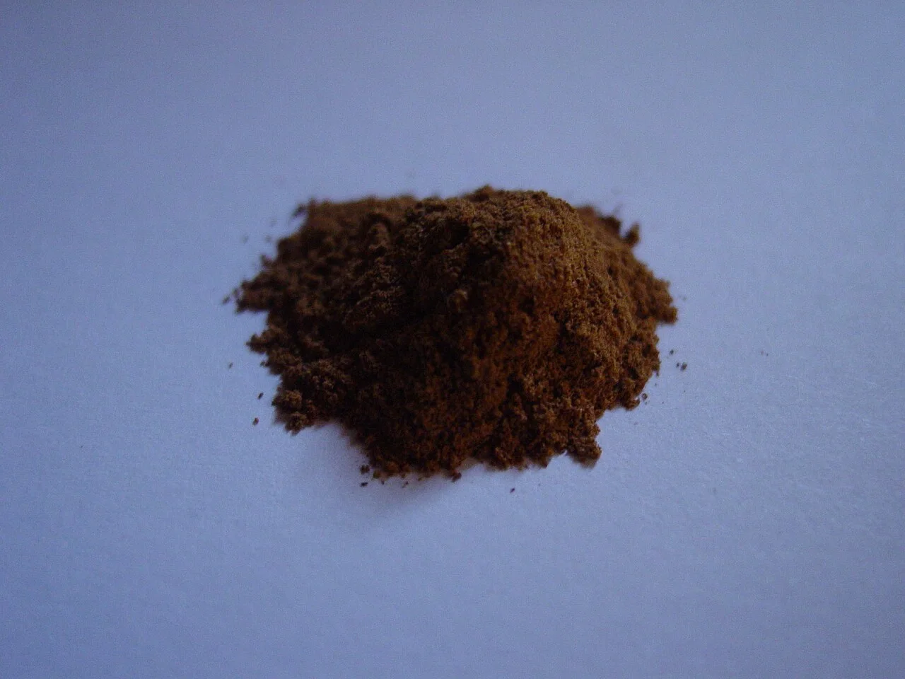 A small mound of ground cinnamon on a pale surface.