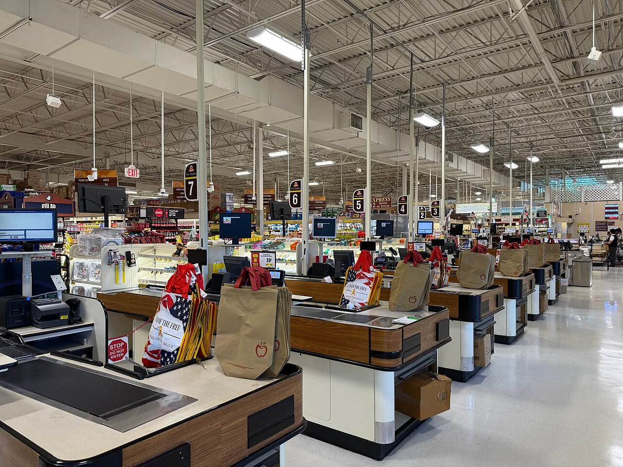 A row of empty supermarket checkout lanes with reusable shopping bags on the counters