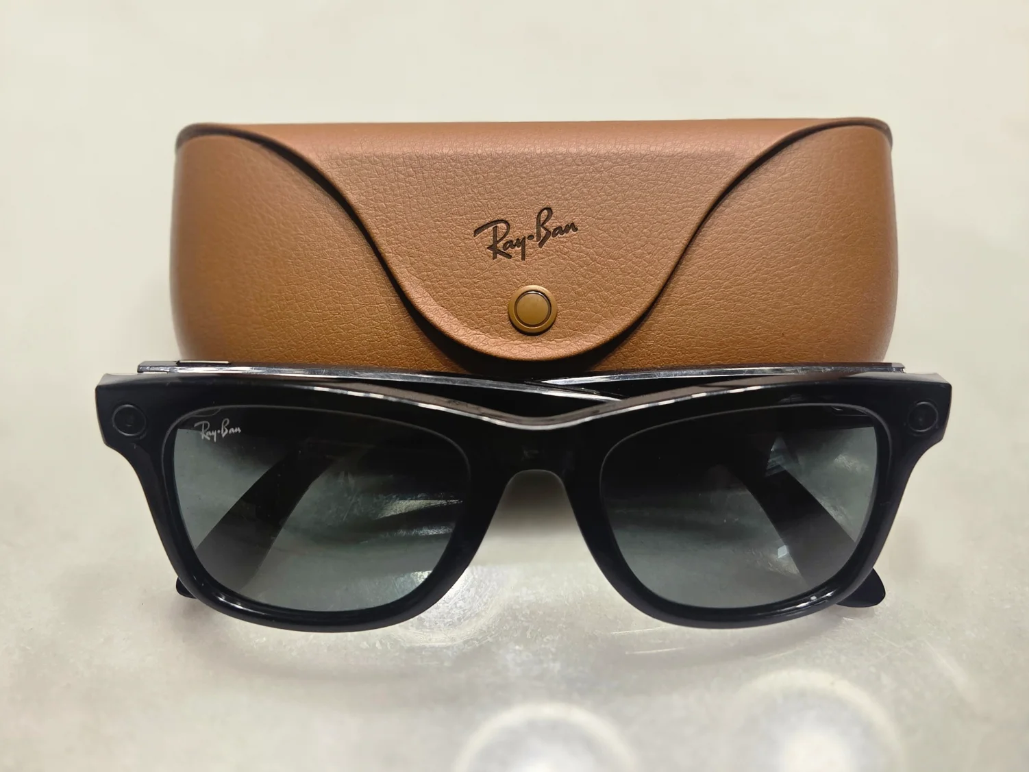 Black Ray-Ban Meta smart glasses in front of their brown charging case