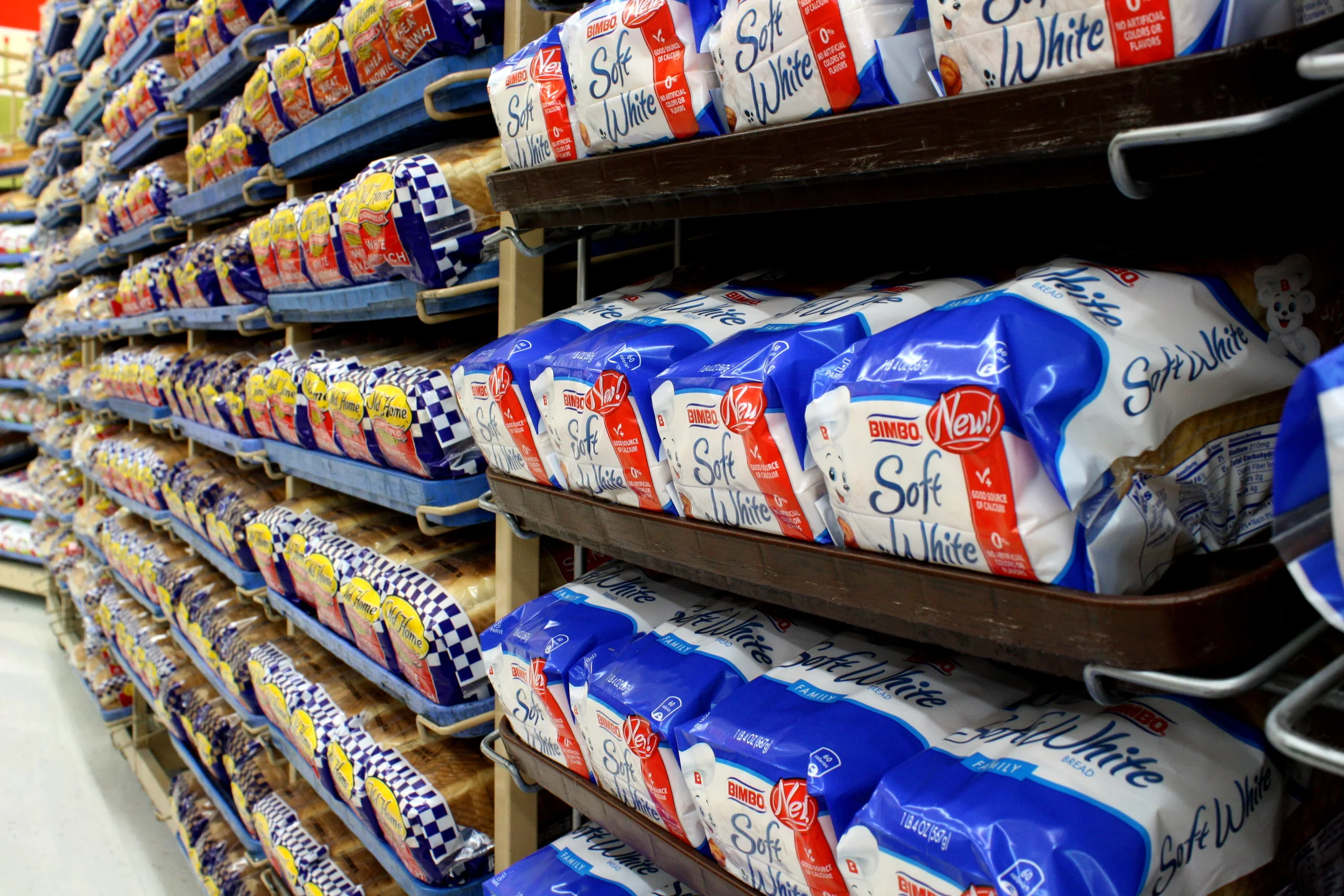 Loaves of white bread arranged on supermarket shelves