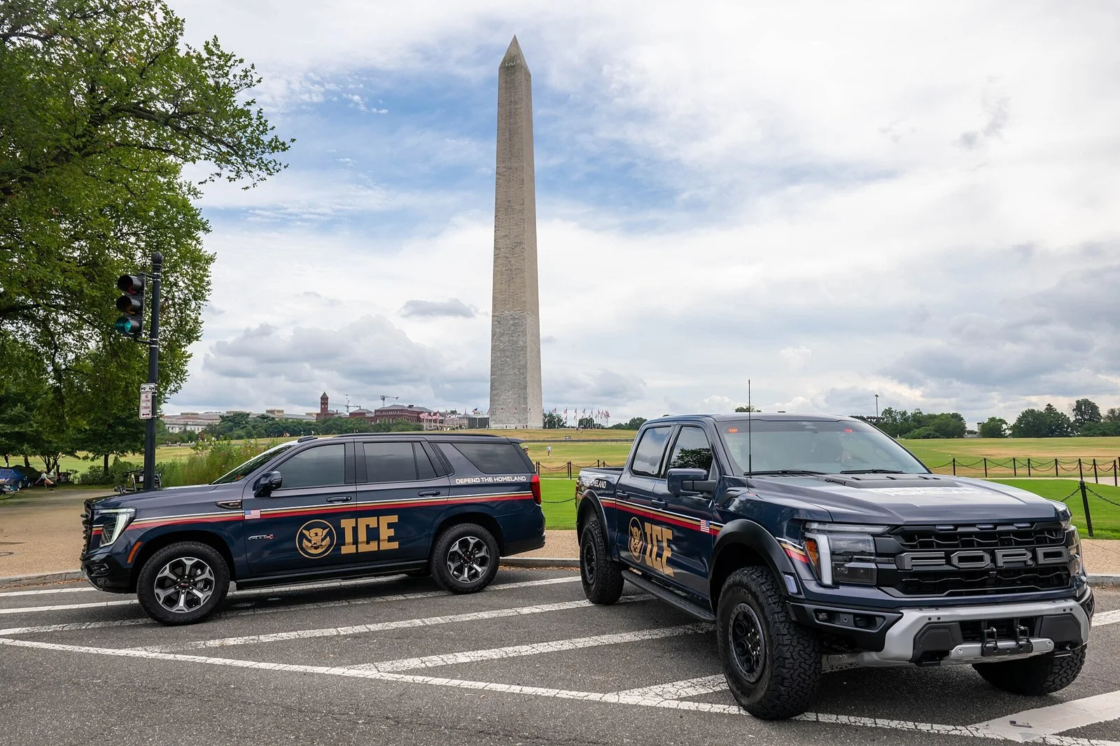 A dark blue SUV and pickup truck with ICE markings parked near the Washington Monument